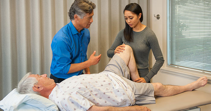 Man and woman physical therapist working on older man